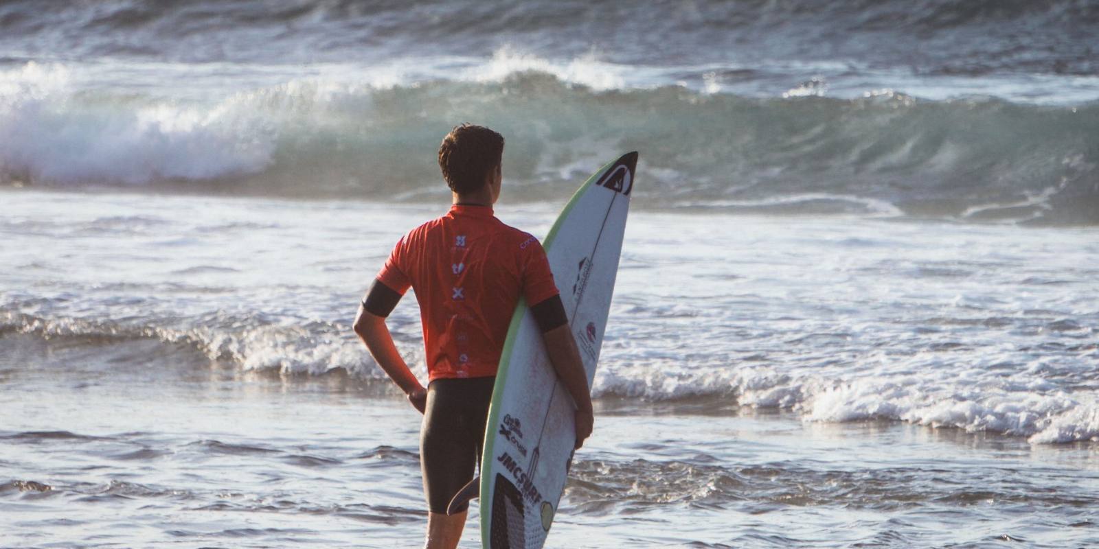 Surfer with a board looking out at the waves